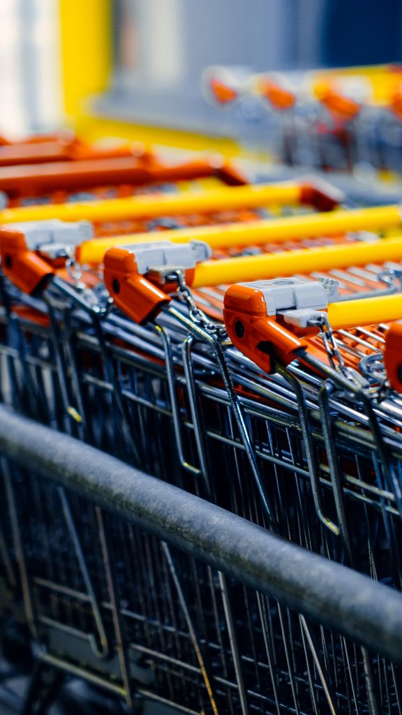 Close-up of orange-handled shopping carts lined up in a store aisle.