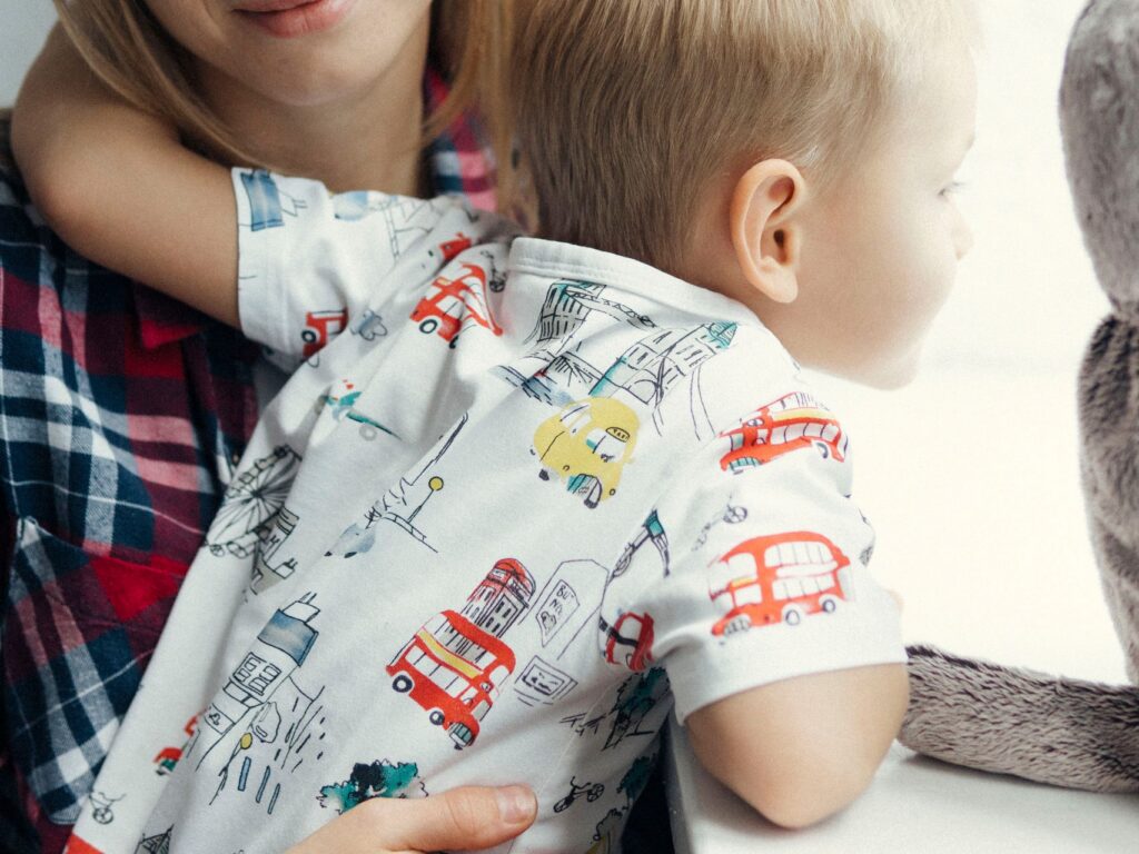 Mother and young son sharing a tender moment while looking out a window, indoors.